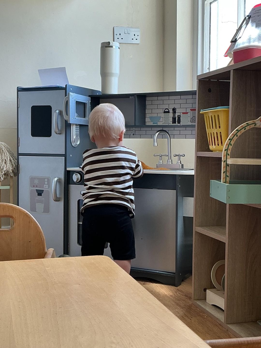 A toddler playing in the play kitchen